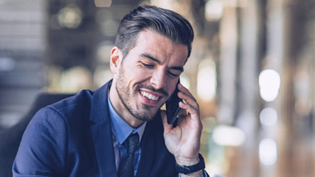 Smiling businessman in a suit talking on his phone, representing professional communication and business success.
