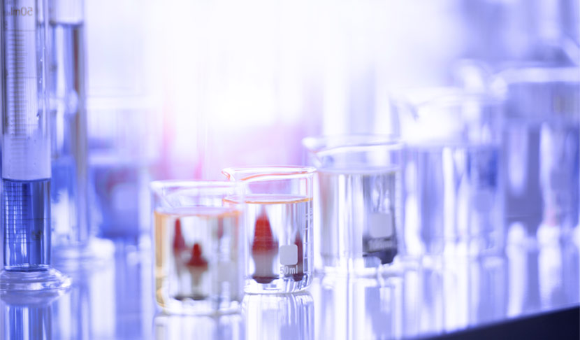 Laboratory glassware with various liquids on a reflective surface, representing scientific experiments and research.